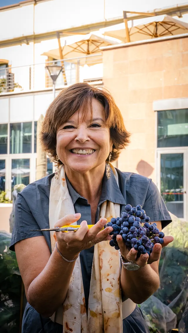 Ritratto di una donna che mostra un grappolo di uva nera fra le mani